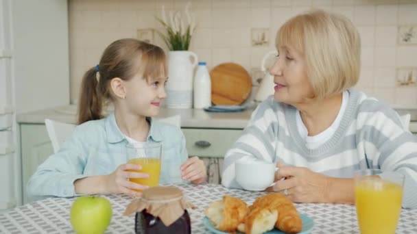 Feliz niño tintineo gafas con feliz anciana abuela hablando y riendo — Vídeos de Stock