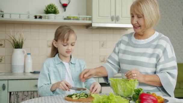 快乐的孩子在做沙拉，然后和老奶奶在厨房桌子边做五块 — 图库视频影像