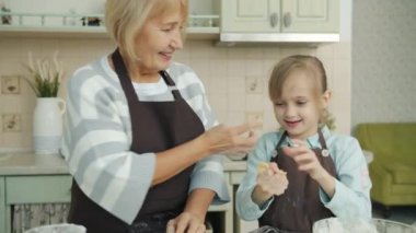 Büyükanne ve torun mutfakta gülüp, bisküvi yaparken eğleniyorlar.