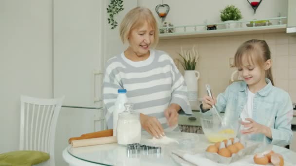 Criança feliz e vovó cozinhar alimentos misturando ingredientes fazendo massa em casa na cozinha — Vídeo de Stock