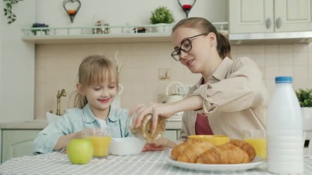 Junge Frau frühstückt und spricht mit süßer kleiner Tochter zu Hause in der Küche — Stockvideo