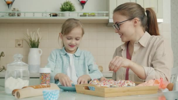 Mouvement lent de la cuisine mère et fille ensemble décorer la pâtisserie et parler dans l'appartement — Video