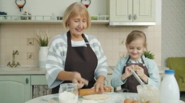 Mutfakta un ile kaplanmış burnuyla çocuklara dokunan neşeli büyükannenin portresi.