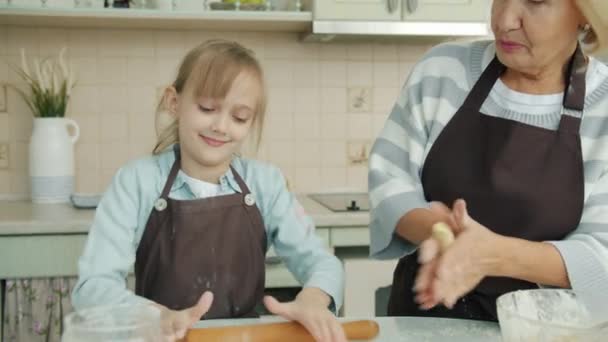 Alegre niño ayudando a la abuela en la cocina de balanceo de masa a continuación, divertirse riendo — Vídeo de stock