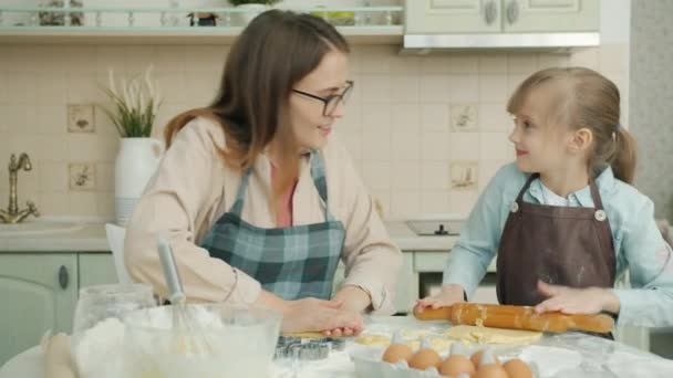 Moeder en dochter bakken koekjes en kletsen binnen met de bakkerij in de keuken — Stockvideo