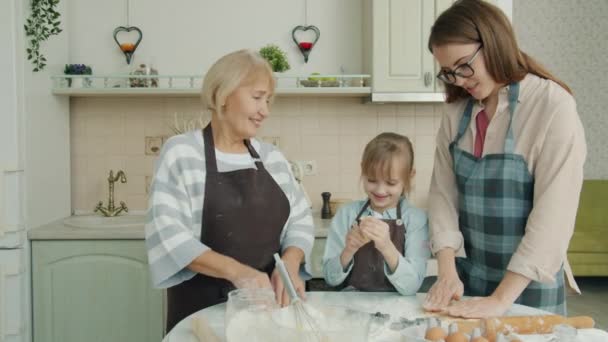 Gelukkig gezin kind, moeder en oma koken bakken en praten in de keuken — Stockvideo