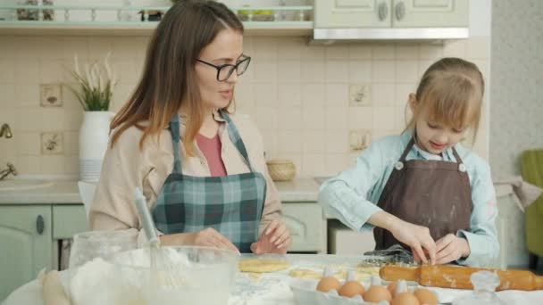 Jonge vrouw en klein meisje maken koekjes en chatten in de keuken thuis — Stockvideo