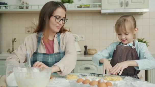 Παιχνιδιάρικο παιδί που διασκεδάζει στην κουζίνα χειροκροτώντας τα χέρια ενώ η μητέρα μαγειρεύει και γελάει — Αρχείο Βίντεο