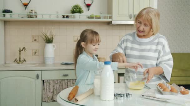 Äldre kvinna och liten flicka matlagning mat gör bakverk blanda ingredienser i köket hemma — Stockvideo