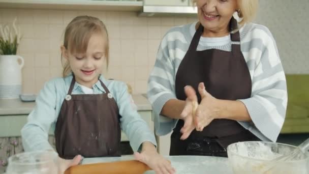 Aranyos gyerek és szerető nagyi főzés a konyhában sodrófa és tészta és szórakozás együtt — Stock videók