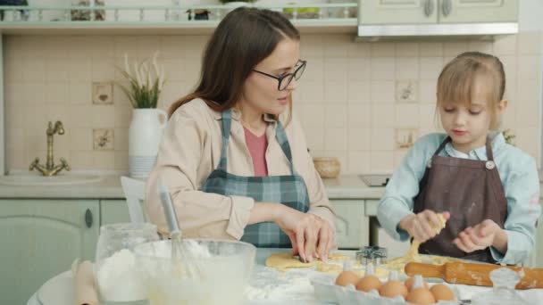 Очаровательный ребенок и любящая мать готовить дома на кухне и говорить — стоковое видео