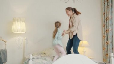 Küçük kız ve neşeli anne evde el ele tutuşup eğleniyorlar.
