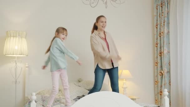 Rallentatore di madre e figlia che ballano a letto divertendosi insieme a casa — Video Stock