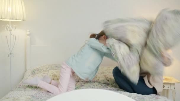 Slow motion av kärleksfull mor leker med glada dotter slåss kuddar sedan kramas — Stockvideo
