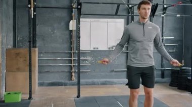 Spor salonunda ip atlayıp atlayan çekici bir genç adam.