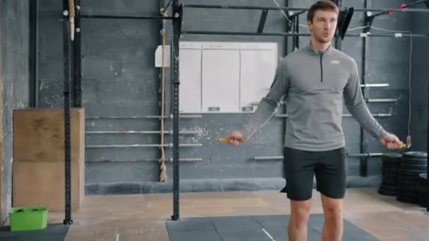 Mouvement lent d'attrayant jeune homme travaillant sur le saut avec corde à sauter dans la salle de gym — Video