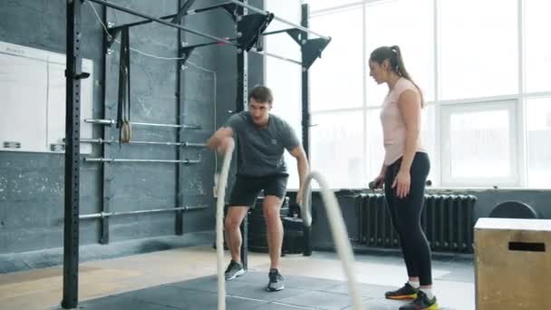 Active guy student robi liny walki crossfit trening z trenerką kobiet w siłowni — Wideo stockowe