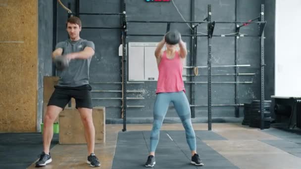 Langzame beweging van jongeren in sportkleding die kraken met kettlebells in de sportschool — Stockvideo