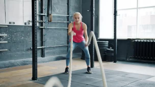 Портрет молодої жінки, що працює з мотузкою під час тренувань з кросфіту в приміщенні — стокове відео