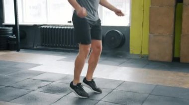 Spor salonunda ip atlarken zıplayan zinde bir gencin yavaş çekimleri.