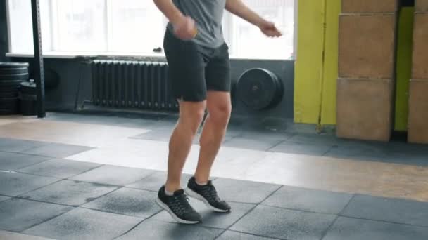 Tilt-up slow motion of fit młody człowiek skacze ze skakanką wewnątrz sali gimnastycznej — Wideo stockowe