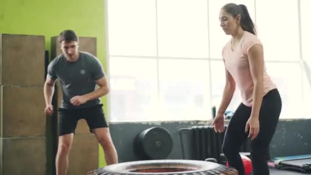 Junge Sportlerin trainiert mit begeistertem Trainer beim Reifenheben — Stockvideo