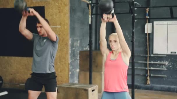 Jeune femme et l'homme de travail avec haltères lourdes squattant et soulevant le poids — Video