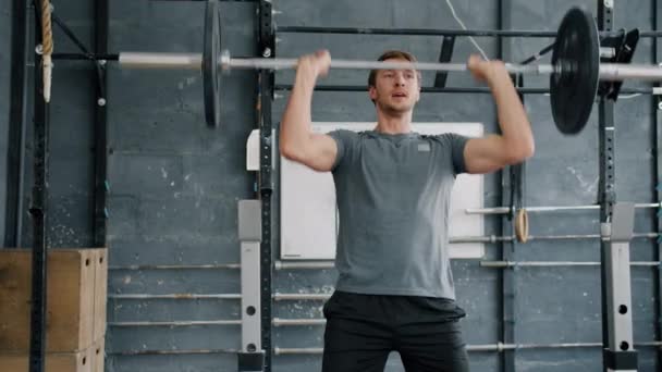 Zeitlupe eines gutaussehenden jungen Sportlers beim Hanteltraining allein im Fitnessstudio — Stockvideo