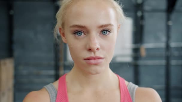 Retrato de una joven deportista seria en ropa deportiva mirando a la cámara en el gimnasio — Vídeo de stock