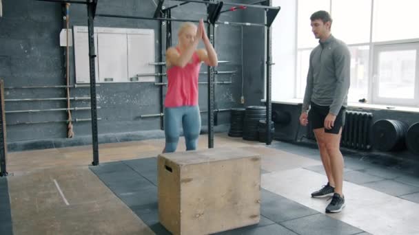 Movimento lento da jovem no sportswear pulando na caixa de madeira no treinamento crossfit — Vídeo de Stock