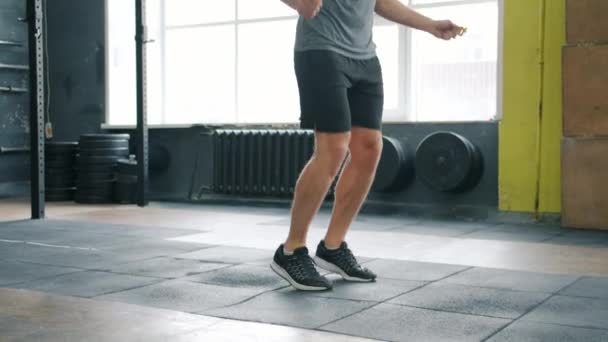 Портрет красивого спортсмена, активного хлопця, який пропускає зі стрибковою мотузкою у спортзалі — стокове відео