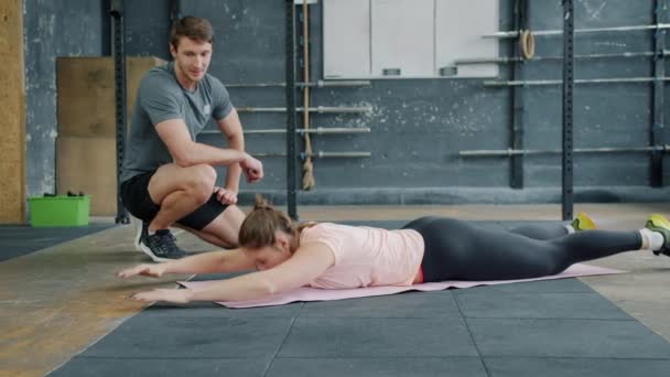 Retrato de la joven deportista haciendo ejercicio en el gimnasio haciendo ejercicio con el instructor en la estera — Vídeos de Stock