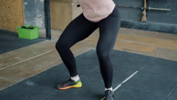 Inclinación de la mujer joven en cuclillas con barra de metal pesado en el gimnasio crossfit haciendo ejercicio solo — Vídeo de stock