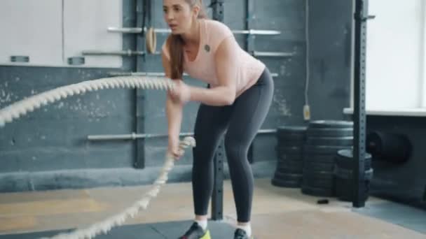 S'adapter à l'entraînement des filles avec des cordes de combat dans la salle de gym tandis que l'entraîneur masculin aidant motivant — Video