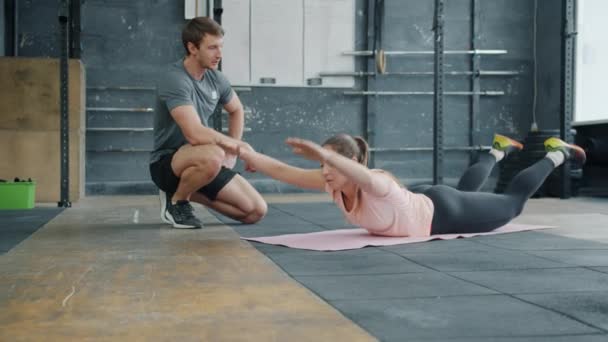 운동을 하는 스포츠 여성, 남자 강사와 함께 매트 위에서 스포츠 훈련을 하는 모습 — 비디오