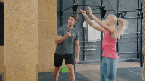 Trage beweging van fit meisje doen bal gooien oefening met ondersteuning van mannelijke trainer — Stockvideo