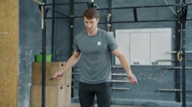 Modern jimnastik salonunda ip atlayan zinde bir adamın ağır çekimde spor yapması.