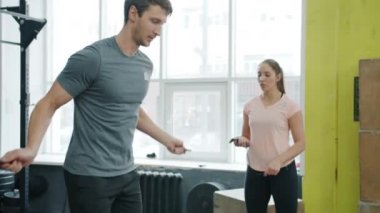 Yavaş çekimde adam atlıyor ip atlıyor kadın eğitmenle beden eğitimi yapıyor.