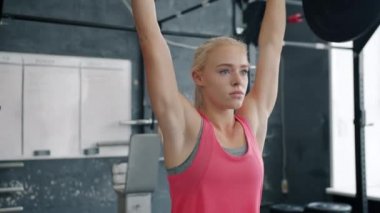 Genç sporcu kadın ağır halter kaldırıyor spor salonunda tek başına spor kıyafetlerini giyiyor.