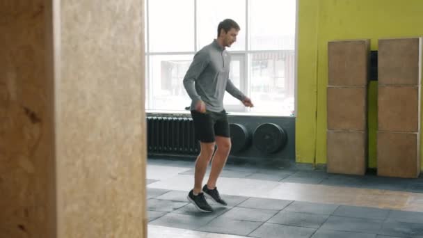 Jongeman springen met springtouw tijdens sporttraining in de sportschool alleen — Stockvideo
