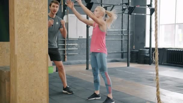 Ernstige jonge sportvrouw oefenen in de sportschool met persoonlijke instructeur gooien bal — Stockvideo