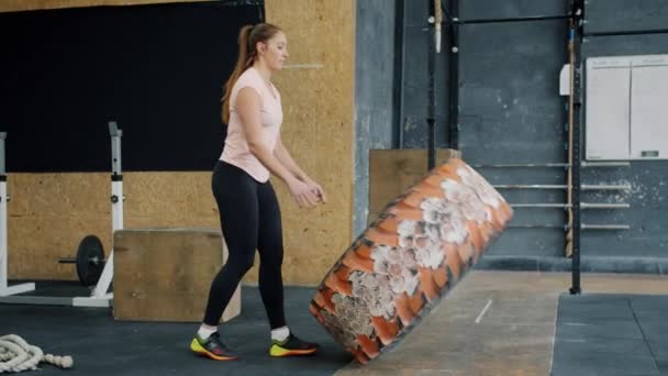 Movimento lento de sportswoman ajuste levantando pneu de borracha pesada trabalhando no ginásio durante o treinamento crossfit — Vídeo de Stock