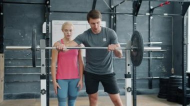 Ağır halter kaldıran genç kız beden eğitimi hocasından tavsiye alıyor.