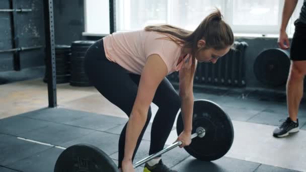 Ajuste deportista levantamiento de la barra de entrenamiento en el gimnasio a continuación, haciendo high-five con instructor — Vídeos de Stock