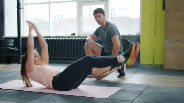 Actieve jonge vrouw oefenen buikspieren training met trainer in de sportschool — Stockvideo