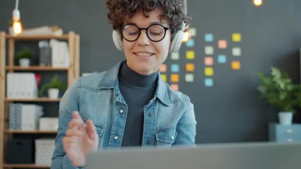 Радостная деловая женщина, работающая с ноутбуком и развлекающаяся музыкой в наушниках — стоковое видео