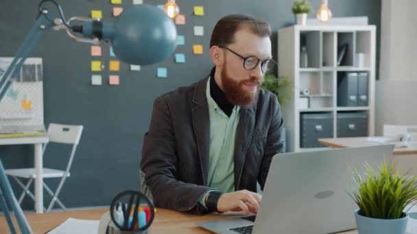 Jovem feliz desfrutando de um trabalho bem sucedido olhando para a tela do computador no escritório — Vídeo de Stock