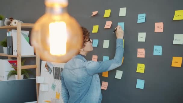 Slow motion of office worker writing on bright sticky notes planning marketing strategy in workplace — Stock Video