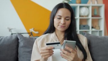 Akıllı telefon ve kredi kartıyla alışveriş yapan mutlu genç bayan.