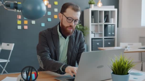 Movimento lento do homem de negócios que trabalha com computador portátil no escritório moderno — Vídeo de Stock